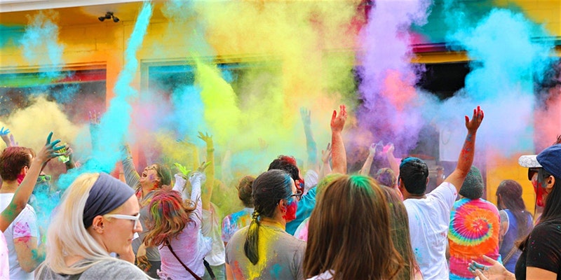 A gathering of people throwing colored powder into the air